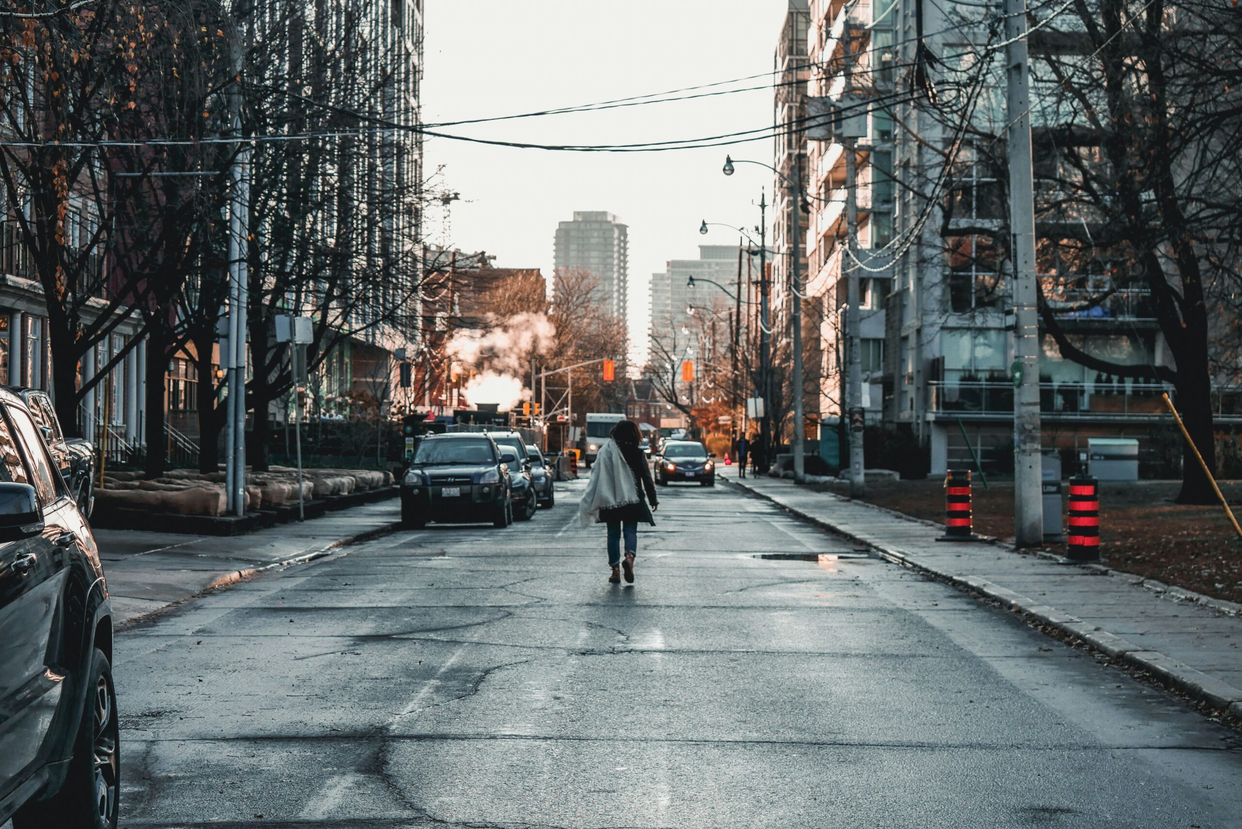 A woman walking alone down a city street at dusk